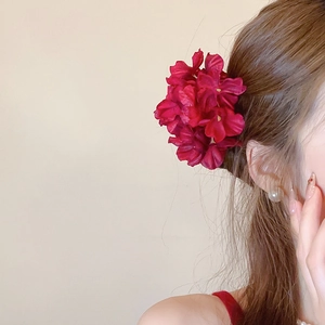 Detailed close-up of a large burgundy fabric flower hair clip worn on long wavy hair