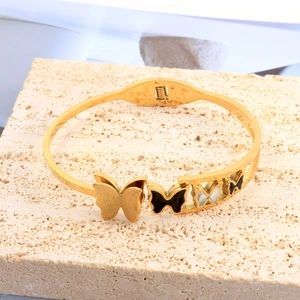 Close-up of gold butterfly bangle with shell inlay on a natural stone base