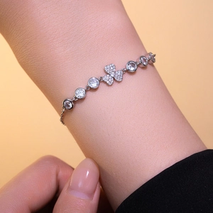 Bracelet élégant en argent avec trèfle et zircons porté au poignet d'une femme