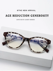 Close-up of tortoise shell cat-eye glasses on a textured white stone surface