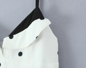 Gros plan sur la robe française à pois montrant le tissu blanc et les bretelles noires