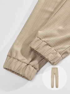 Detail of beige plaid textured trousers featuring elastic ankle cuffs and woven fabric