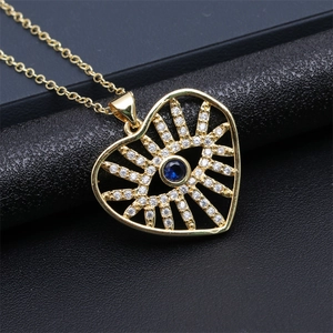 Detailed macro shot of golden heart-shaped evil eye pendant with blue crystal and rhinestones