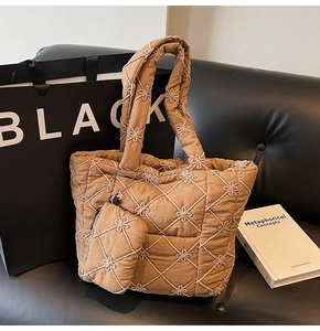 Close-up of quilted floral latte brown tote bag and mini pouch on a black sofa
