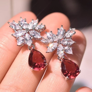 Detailed close-up of pear-shaped red zircon earrings with floral marquise crystal studs