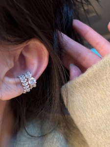 Close-up of sparkling silver cubic zirconia ear cuff with leaf and round diamond patterns