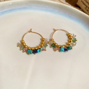 Bohemian gold hoop earrings with multi-color natural stones on a ceramic jewelry tray