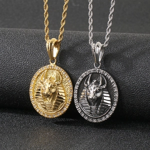 Vue détaillée des pendentifs Anubis or et argent avec strass sur un fond noir texturé