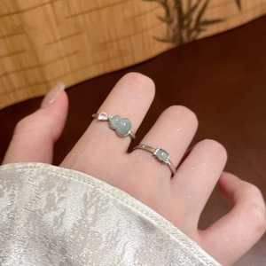 Silver rings featuring light green jade gourd and bead charms on elegant hand model