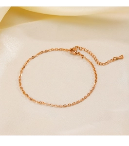 Détail d'une chevillère en acier inoxydable or rose sur un tissu en soie élégant