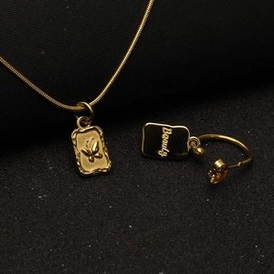 Detailed view of golden necklace and earrings with engraved butterfly and Beauty pendant
