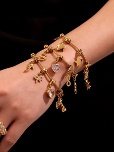 Détail de l'ensemble de bracelets dorés avec breloques cœur zircon, étoile et infini