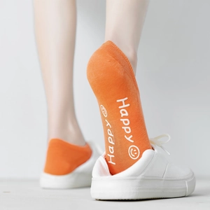 Detail of orange cotton ankle sock with Happy smiley face worn with white sneakers