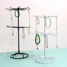Rotating metal jewelry display stands in black and white with necklaces and bracelets