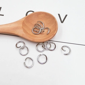 Detail of silver metal open jump rings for DIY jewelry making on a decorative wooden spoon