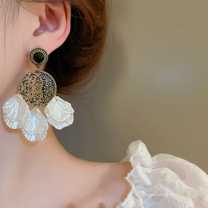 Vue macro de boucles d'oreilles vintage avec pétales en nacre et détails dorés