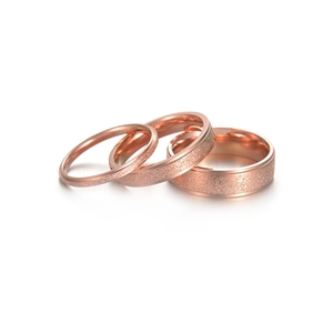 Detailed view of three rose gold 2mm frosted stainless steel rings on white background