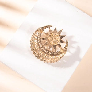 Macro detail of a vintage gold sun and crescent moon brooch with relief textures