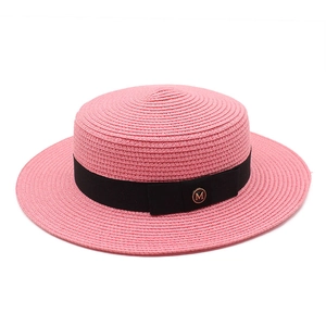 Détail de la texture d'un chapeau canotier rose avec ruban noir et boucle M dorée