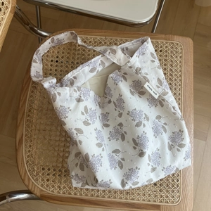 Light purple floral cotton shoulder bag with simple wish label on a woven chair