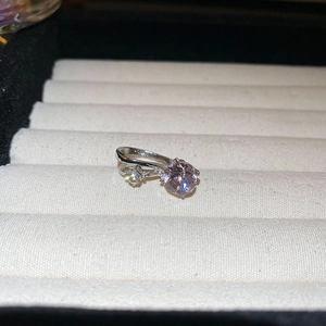 Gros plan d'une bague en argent avec pierre violette et diamants dans un écrin à bijoux