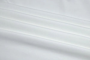 Gros plan du tissu de robe blanche élégante montrant la maille fine et le drapé soyeux