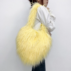 Detailed texture of vibrant bright yellow faux fur on a heart-shaped crossbody shoulder bag