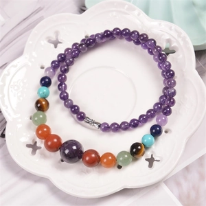 Macro detail of colorful chakra natural stone beads on a white ceramic flower tray