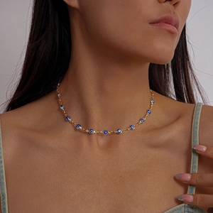Close-up of golden necklace featuring blue evil eye charms worn by a model