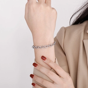 Close-up of a chunky silver stainless steel link bracelet on a woman wrist with a blazer