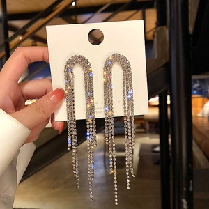 Macro shot of silver tassel earrings with sparkling rhinestones and U-shaped base