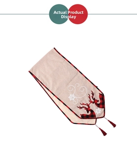 Detail of Christmas table runner with reindeer embroidery, plaid border and red tassel