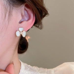 Detail of 18k gold plated cream acrylic flower stud earring worn on model's ear