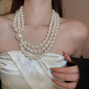Detail showing the layered white pearl necklace with varying bead sizes on a model