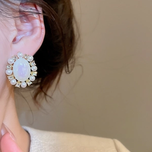 Macro shot of vintage gold stud earrings with oval pearl and sparkling crystal accents