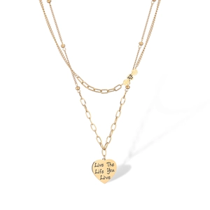 Macro detail of gold-plated heart pendant engraved with Live The Life You Love text