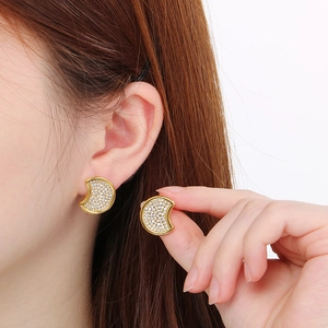 18k gold plated crescent moon earrings with cubic zirconia shown on ear and held