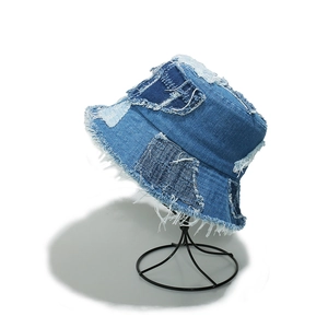 Detail of blue denim bucket hat featuring patchwork design and distressed frayed edges