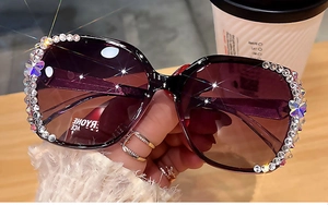 Détail macro de lunettes de soleil oversize avec verres dégradés violets et papillon strass
