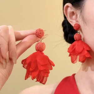 Close-up of red raffia and chiffon flower petal drop earrings for a vacation look