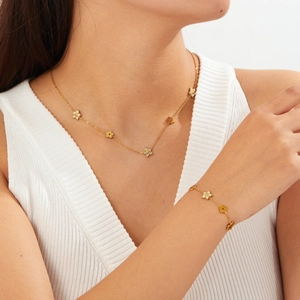 Close-up of gold-plated flower and star necklace set with zircon on model