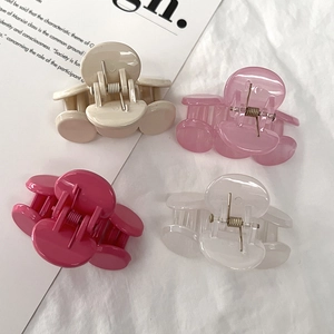 Set of four sweet pink and beige round hair claw clips on a white fabric background