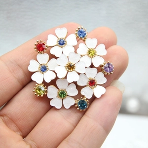 Spilla fiore in smalto bianco con cristalli multicolore su una base placcata in oro