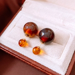 Macro shot of Maillard resin round earrings in amber and gold on beige velvet