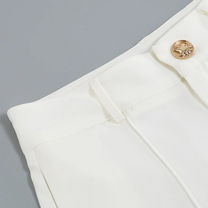 Close-up of white trousers featuring a golden button and premium twill fabric detail