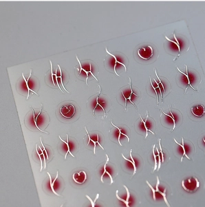 Macro view of metallic tribal line nail stickers with red heart accents on clear film