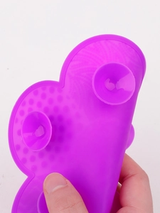 Macro detail of purple heart-shaped silicone makeup brush cleaner with suction cups