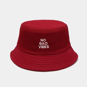 Detail of red cotton bucket hat with white 'NO BAO VIBES' embroidery and reinforced stitching