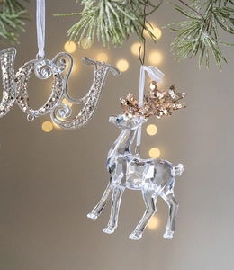 Detail of transparent acrylic reindeer ornament with gold sequins on a Christmas tree