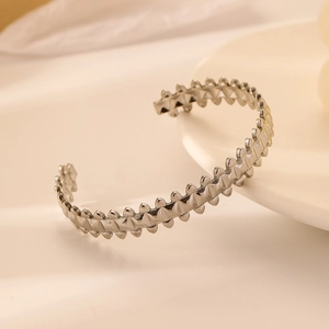 Detail of silver stainless steel open bangle featuring sun coin and rivet accents